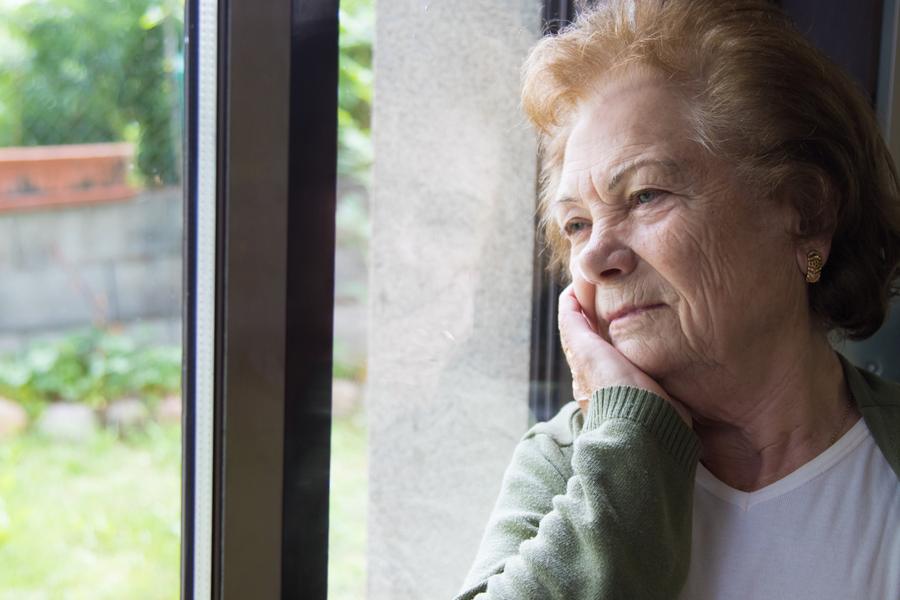 An older woman waiting alone by her window